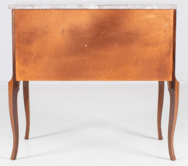 Front view of a vintage French Louis XVI style wooden commode with two drawers, a central oval floral marquetry design, and a red marble top.