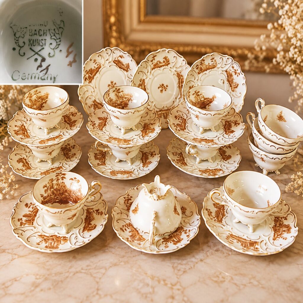Rare vintage German Schaubach Kunst porcelain tea set featuring three-footed cups and scalloped saucers with gold-gilded rococo Courting Couple scenery on a white glaze background.