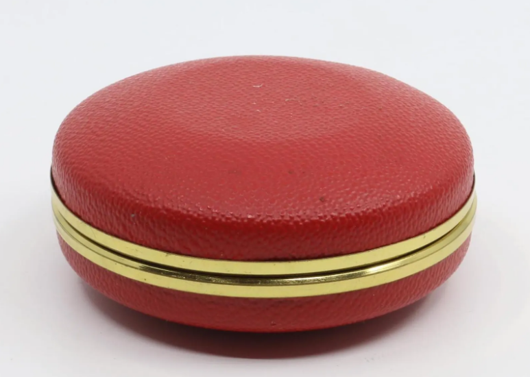 Vintage German mechanical travel alarm clock, c. 1960s, featuring a red folding clam shell case with brass-toned trim, white Arabic numeral dial and luminous-style hands.