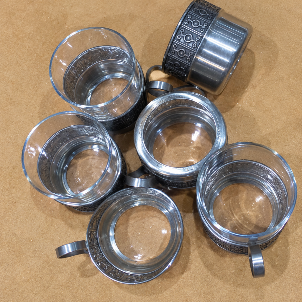 Set of six vintage Swedish clear glass teacups with decorative silver-tone metal holders, embossed geometric patterns, and curved handles, dated  c.1960s